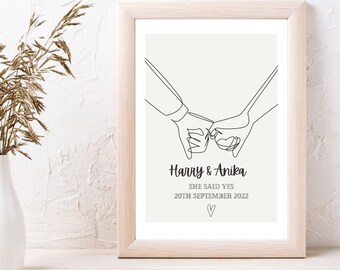 May include: A minimalist line art print of two hands holding each other, with the text "Harry & Anika" and "She said yes 20th September 2022" below.