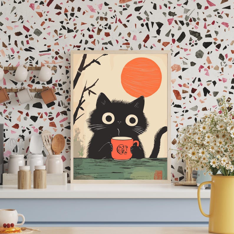 May include: A framed art print featuring a black cat holding an orange mug with a logo. The cat is set against a backdrop of a rising orange sun and a light beige sky. The artwork has a minimalist, cartoon style.