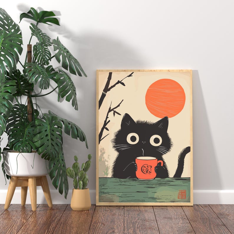May include: A framed art print featuring a black cat with large eyes, holding an orange mug. The cat is set against a cream background with an orange sun and stylized branches. The print has a Japanese aesthetic.