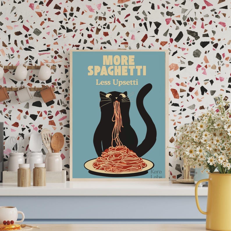 May include: A rectangular wall art print with a light blue background featuring a black cat eating a large pile of red spaghetti on a plate. The text reads MORE SPAGHETTI Less Upsetti in yellow and white letters. The artist name Kara Labs is visible.