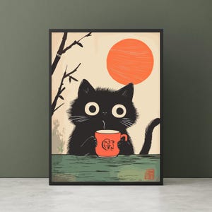 May include: A framed art print featuring a black cat with large white eyes, holding a red mug. The cat is set against a backdrop of a rising orange sun and a beige sky. A branch and leaves are on the left side of the image.