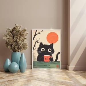 May include: Framed art print featuring a black cat holding a red mug with a graphic design. The cat is set against a backdrop of a rising orange sun and stylized branches. The artwork has a minimalist, Japanese-inspired aesthetic.