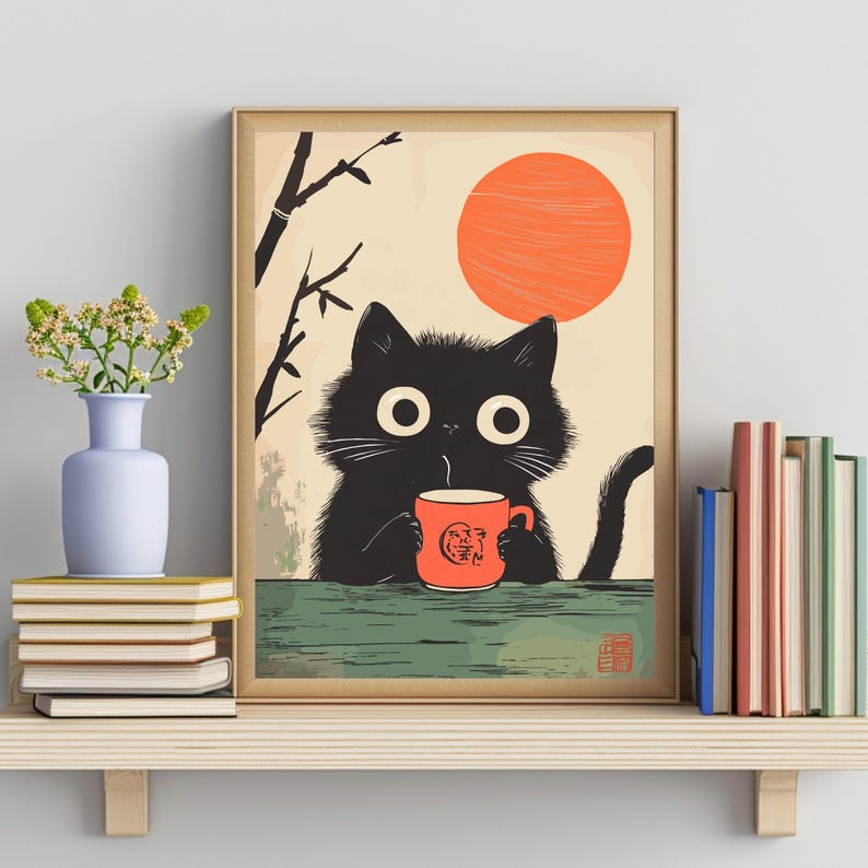 May include: A framed art print featuring a black cat with large eyes, holding a red mug. The cat is set against a beige background with an orange sun and bamboo branches. A shelf below holds books and a vase with flowers.