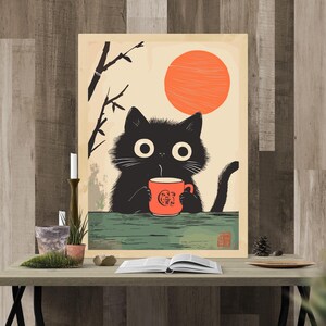May include: A whimsical art print featuring a black cat with large eyes, holding a red mug with a logo, set against a backdrop of a rising orange sun and bamboo. The cat is positioned on a green surface, creating a charming, illustrative scene.