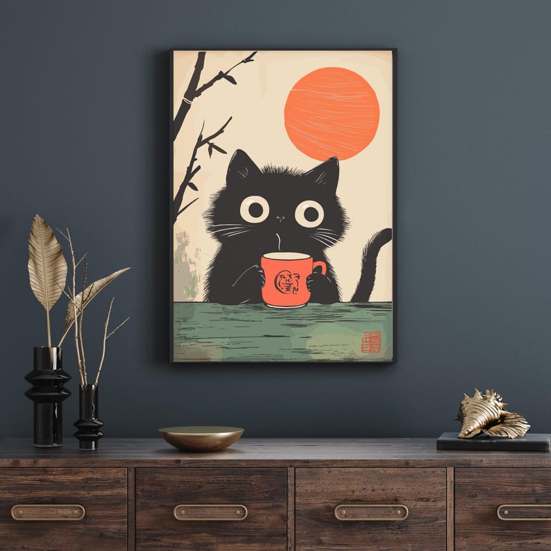 May include: A framed art print featuring a black cat holding an orange mug with a design. The cat is set against a backdrop of a rising orange sun and a light beige sky. The art has a Japanese aesthetic.