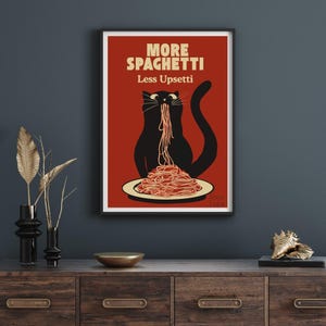 May include: A rectangular wall art print featuring a black cat eating spaghetti on a dark red background. The text at the top reads MORE SPAGHETTI Less Upsetti in cream-colored letters. The cat is centered, facing forward with a long strand of pasta.