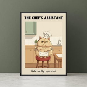 May include: A framed print featuring a cartoon cat in a chef's hat and apron, sitting on a stool in a kitchen setting. The text at the top reads "THE CHEF'S ASSISTANT" and below, "(Who mostly supervises)". The cat has a grumpy expression.
