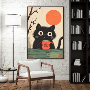 May include: A framed art print featuring a black cat holding an orange mug with a logo, set against a backdrop of a rising sun and bamboo branches. The cat has large, round eyes.