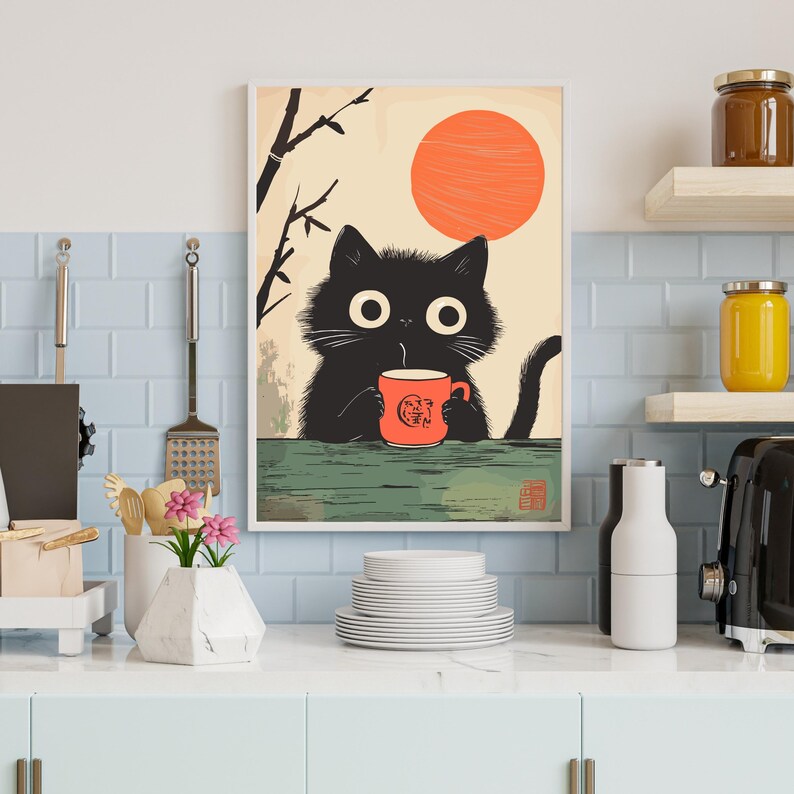 May include: A framed art print featuring a black cat holding a red mug with a graphic design. The cat is set against a backdrop of a rising orange sun and a minimalist landscape. The print is displayed in a kitchen setting.