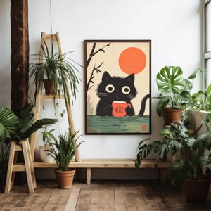 May include: Framed art print featuring a black cat with large eyes, holding an orange mug. The cat is set against a backdrop of a rising orange sun and a beige sky. The artwork has a Japanese aesthetic.