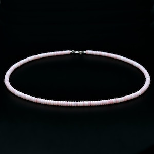 以下が含まれることがあります： 小さな丸い薄ピンク色のビーズで構成された繊細なネックレス。ビーズは一本の紐に繋がれ、銀色の留め金で固定されています。ネックレスは黒い背景に表示されています。