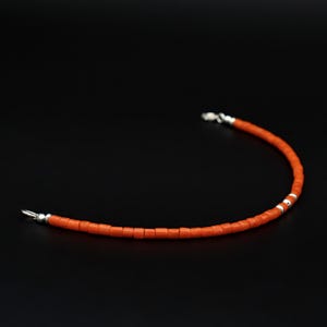 Peut inclure: Un bracelet simple en perles orange avec des fermoirs argentés.
