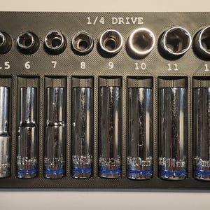 May include: A black socket organizer with 1/4 drive sockets ranging from 4mm to 14mm. The sockets are chrome with blue accents. The sizes are printed in white on the black organizer.