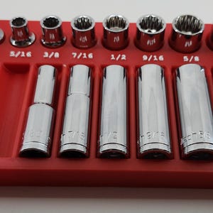 May include: A red socket organizer tray holding a set of chrome sockets. The sockets are labeled with their sizes, ranging from 3/4 to 11/16 inches. The tray has slots for the sockets.