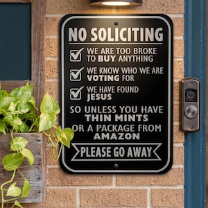 May include: Black rectangular metal sign with white text that reads "NO SOLICITING." The sign humorously lists reasons for not soliciting, including being broke, knowing who they are voting for, and having found Jesus. The sign ends with "PLEASE GO AWAY."