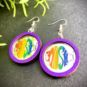 May include: A pair of purple wooden earrings with a rainbow mirror image of the word "FISH" on each earring.
