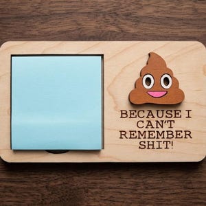 May include: Wooden memo board with a light blue sticky note pad and a brown poop emoji. The text "BECAUSE I CAN'T REMEMBER SHIT!" is printed below the emoji.