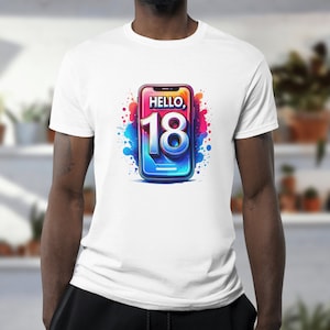 May include: White t-shirt featuring a colorful graphic of a smartphone with the text "HELLO, 18". The design includes vibrant splashes of blue, pink, and yellow, creating a bold and eye-catching look. The shirt is made of a soft material.