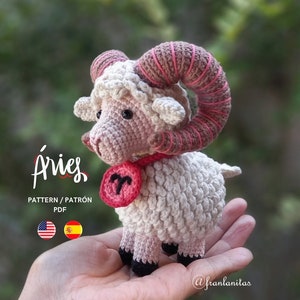 Può includere: Ariete in amigurumi all'uncinetto, segno zodiacale, con corna rosa e un simbolo zodiacale rosso e bianco. L'ariete è seduto in una mano. Il testo "Aries" e "PATTERN/PATRÓN PDF" è sotto l'ariete.