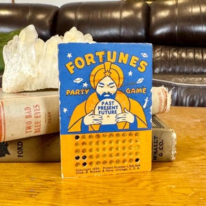 May include: A vintage 1939 Fortunes Party Game card featuring a blue and yellow illustration of a figure holding a crystal ball labeled Past Present Future. The card has a grid of small circular holes and text at the bottom including copyright 1939, Patent Number 1,309,349, and Chas. A. Brewer & Sons, Chicago, U.S.A.