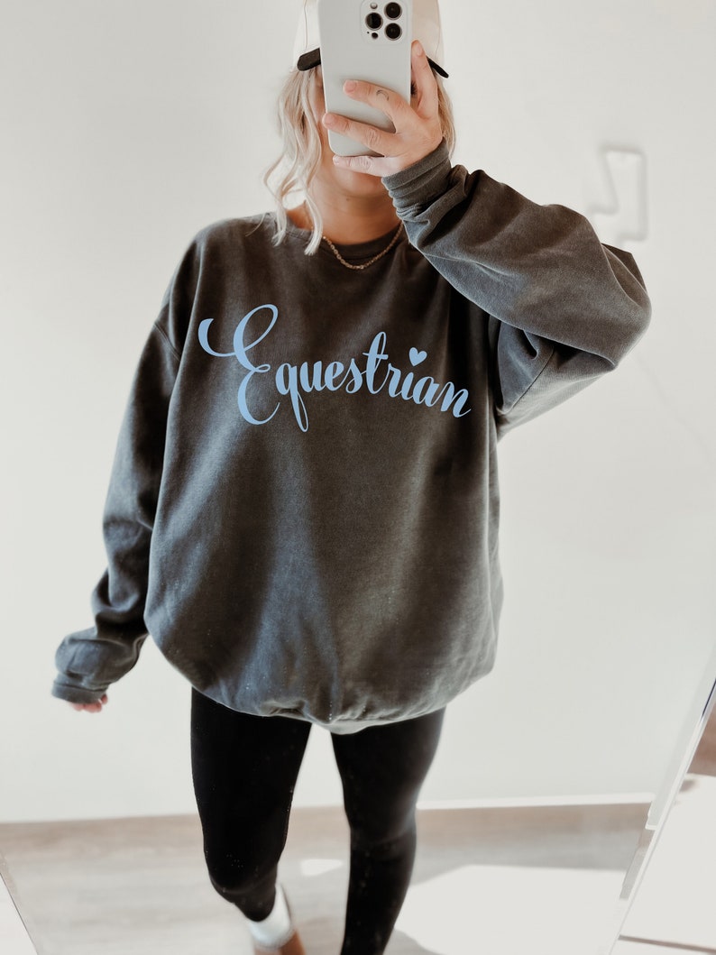 May include: A dark gray sweatshirt with the word "Equestrian" in light blue lettering with a small blue heart.