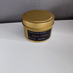 Puede incluir: Un tarro de vela dorado con una etiqueta negra que dice "Smells Like Lando Norris" y "Cire de Soja Parfum&eacute;e".