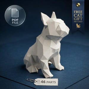 Puede incluir: Una escultura de papel blanco de estilo low-poly que representa un perro sentado con orejas puntiagudas. Una pequeña etiqueta blanca sujeta con un clip metálico dice 46 PARTS. Un icono circular indica PDF FILE y una cinta azul muestra FREE CAT GIFT INCLUDED.