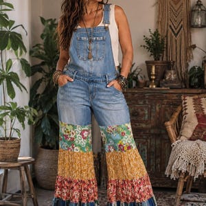May include: Light blue denim overalls featuring a bib pocket and wide-leg pants. The lower portion of the legs consists of tiered, multicolored floral and patterned fabric panels in shades of green, yellow, red, and blue, ending in a ruffled hem.