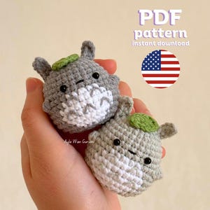 May include: A crochet pattern for making two small grey and white Totoro plushies with green leaves on their heads. The pattern is available as a PDF instant download.