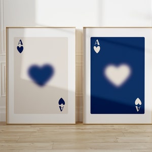 May include: Two framed prints of the Ace of Spades playing card. The card on the left has a white background with a blue heart and the card on the right has a blue background with a white heart.