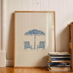 May include: A framed illustration of two blue and white striped deckchairs under a blue and white striped umbrella.