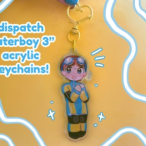 May include: A 3-inch acrylic keychain featuring a cartoon character in a blue and yellow wetsuit with goggles. The keychain has a gold-colored heart-shaped clasp and the text "dispatch waterboy 3" acrylic keychains!" in blue.