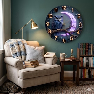 May include: A round wall clock featuring a blue owl perched on a branch in front of a purple crescent moon. The clock face is dark blue with glowing orange numbers. The clock is a decorative item for a living room.
