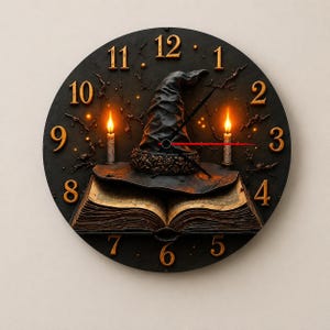 May include: A round wall clock with a black face featuring gold-colored numbers from 1 to 12. The center displays an open book with a dark pointed hat resting on top. Two lit candles stand on either side of the hat, and thin black clock hands.