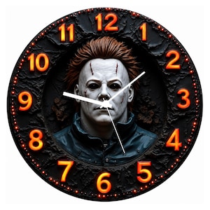 May include: A round wall clock featuring a three-dimensional relief of a pale, masked figure with dark eyes and brown hair. The clock face has a textured black background with glowing orange numbers from 1 to 12 and two white clock hands.