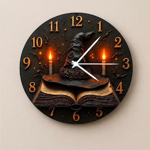 May include: A round wall clock with a black face featuring gold numbers one through twelve. The center displays an open book with a pointed hat resting on top, flanked by two lit candles. Three white clock hands are positioned in the center.