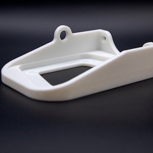 May include: White plastic wall mount with a rectangular opening and a small hole on the top.