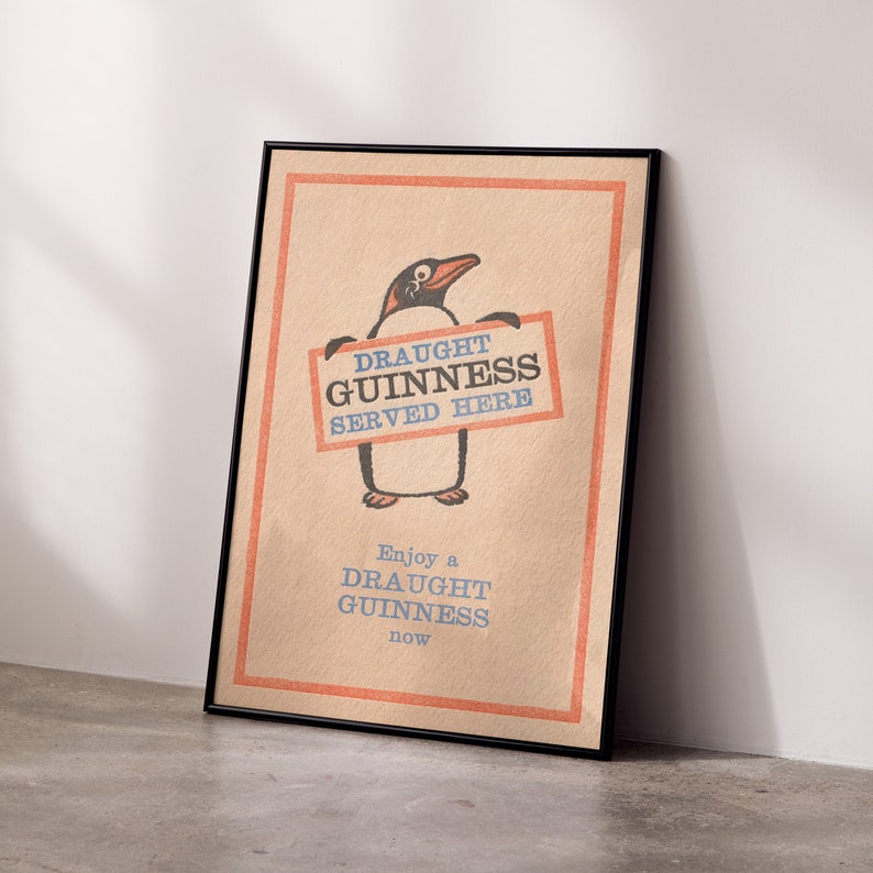 Puede incluir: Un p&oacute;ster de estilo vintage con un ping&uuml;ino de dibujos animados sosteniendo un cartel que dice "Draught Guinness Served Here". El p&oacute;ster tiene un fondo beige con un borde rojo y el texto "Enjoy a Draught Guinness now" en la parte inferior.