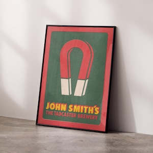 Peut inclure: Une affiche encadrée avec un schéma de couleurs rouge et vert. L'affiche présente un grand aimant en fer à cheval rouge avec le texte "John Smith's The Tadcaster Brewery" en jaune.