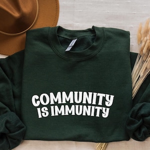 May include: Forest green sweatshirt with the text "COMMUNITY IS IMMUNITY" in white lettering.