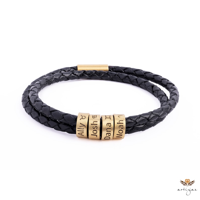 K&ouml;nnte beinhalten: Schwarzes Lederarmband mit geflochtenem Design und vier goldenen Perlen, die mit den Namen Ally, Josh, Dana und Noah graviert sind.