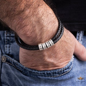 K&ouml;nnte beinhalten: Ein schwarzes Lederarmband mit silbernen Perlen, auf denen "I love", "Keri", "Drue" und "Austin" steht.