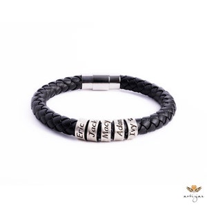 May include: Black braided leather bracelet with silver-tone name beads. The bracelet features a magnetic clasp and is personalized with the names "Eric", "Jack", "Macy", "Adam", and "Ivy". A stylish and personalized accessory.