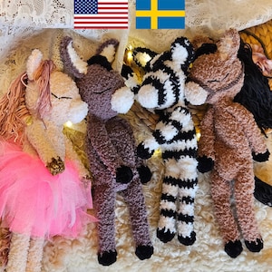 May include: A collection of handmade plush animal toys, including a pink pony with a tutu, a purple donkey, a zebra, and a brown horse. The toys are made of soft, textured material and are arranged on a white surface.