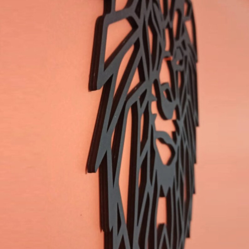 May include: A black wall art piece featuring a geometric, angular lion head design. The cutout structure is composed of sharp, intersecting lines that form the mane and facial features of the lion, presented in a flat, matte black finish.