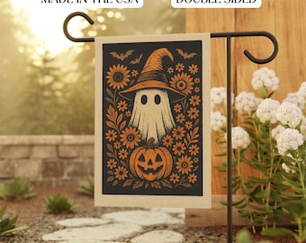May include: Double-sided Halloween garden flag featuring a ghost wearing a witch hat, surrounded by orange flowers and a jack-o'-lantern. The flag is black with orange and cream-colored graphics. Text at the top reads "MADE IN THE USA" and "DOUBLE SIDED".