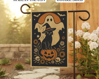 May include: Double-sided Halloween garden flag featuring a black cat wearing a witch hat, sitting on a jack-o'-lantern. A ghost and bats are in the background. The flag is black with orange and tan accents. Text on the flag reads "Made in the USA".