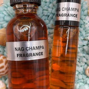 Pu&ograve; includere: Due bottiglie di olio profumato Nag Champa. Le bottiglie sono entrambe di colore ambrato e hanno tappi neri. La bottiglia pi&ugrave; grande ha un'etichetta argentata con il testo "Nag Champa Fragrance" stampato su di essa. La bottiglia pi&ugrave; piccola ha un'etichetta argentata con il testo "Nag Champa Fragrance" stampato su di essa.