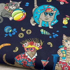 May include: Navy blue fabric with a repeating pattern of cats in sunglasses and tropical attire. The cats are lounging with beach balls, inflatable rings, and cocktails. The fabric also features seashells and tropical flowers.
