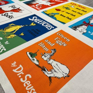 May include: A fabric panel featuring colorful squares with illustrations and text from Dr. Seuss books. The squares include titles like "Green Eggs and Ham," "Sneetches," and "Fox in Socks," with vibrant colors and whimsical characters.